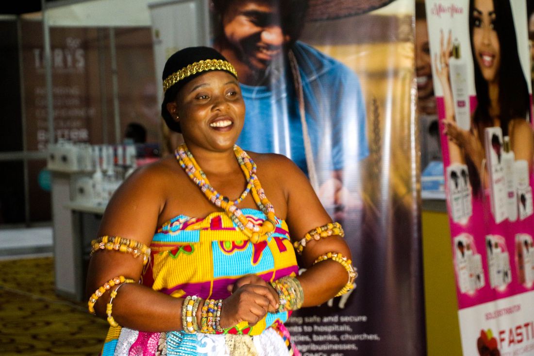 Two Ghanaian women dressed in kente cloth and beads at a celebration
