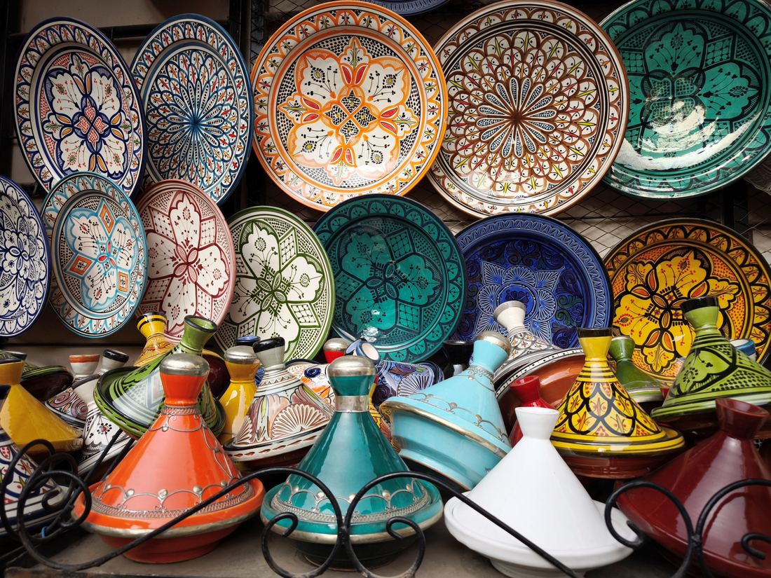 Stacks of painted ceramic plates and tagine pots for sale in a Moroccan market