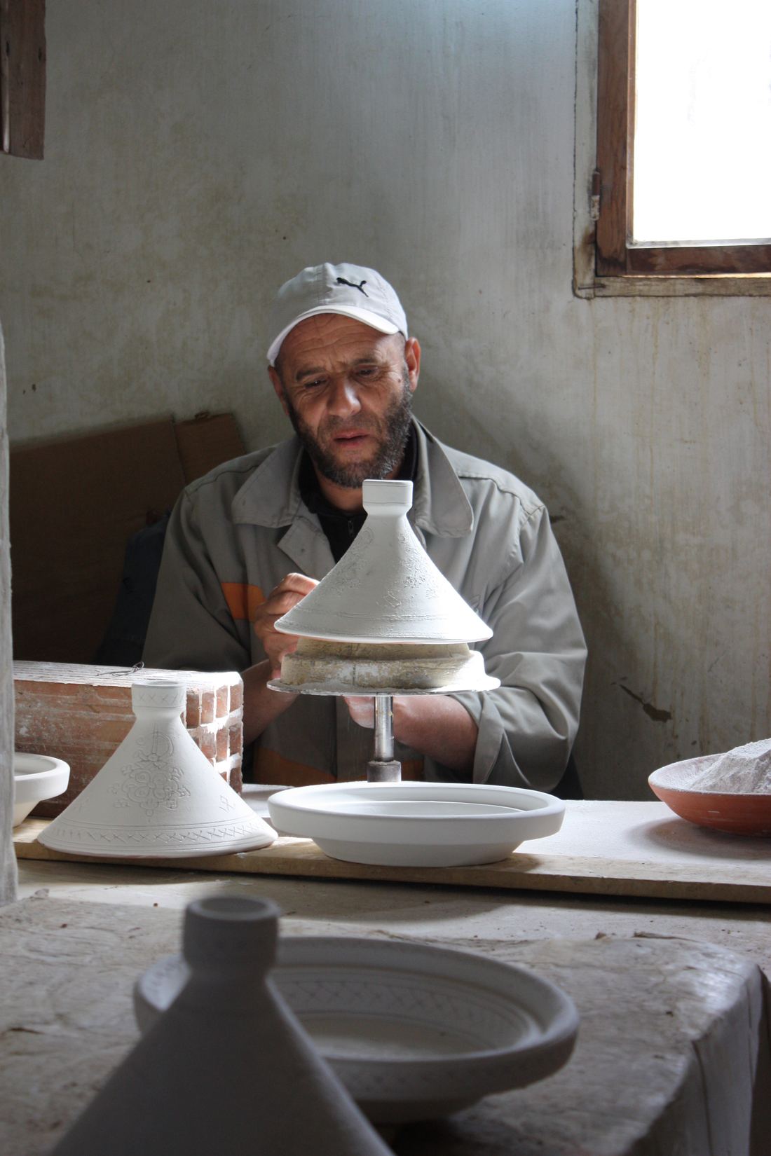 A Moroccan potter shaping a clay tagine on a wheel