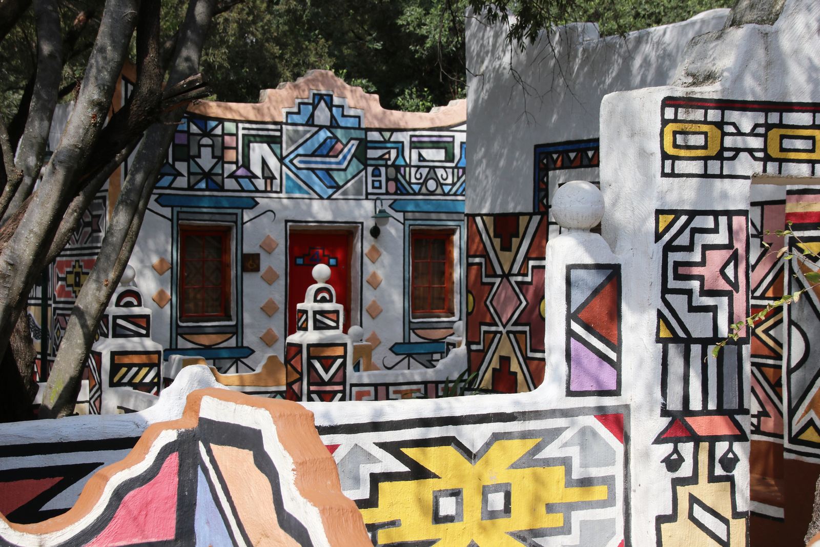 Walls of a homestead painted with bold geometric Ndebele patterns in black, white and bright colors